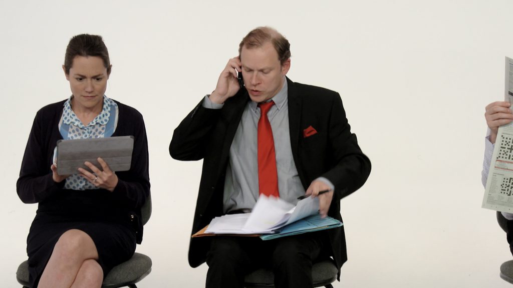 Robert Webb on the phone next to woman on her ipad.