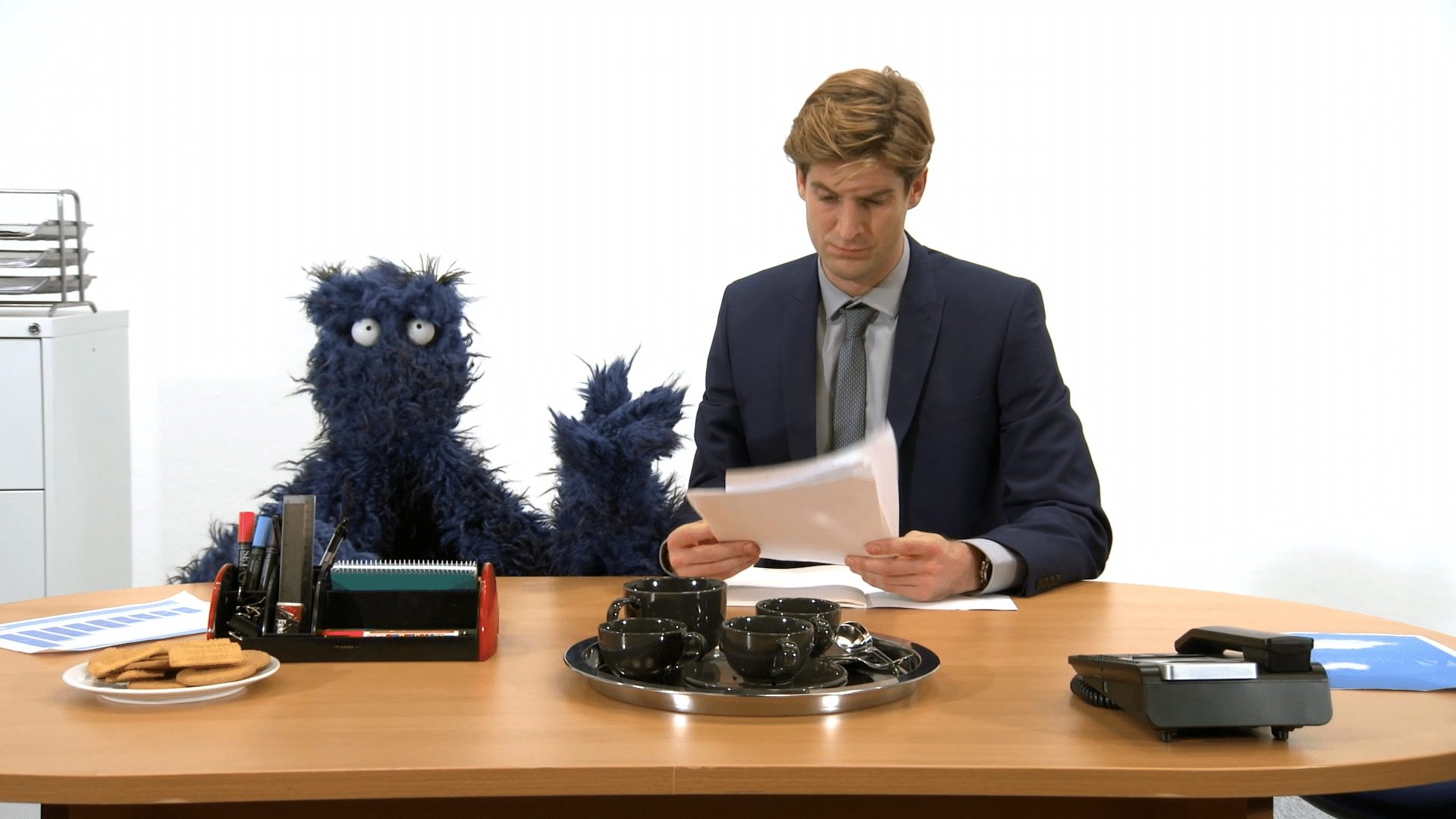 Man looking at papers at a desk next to a monster.