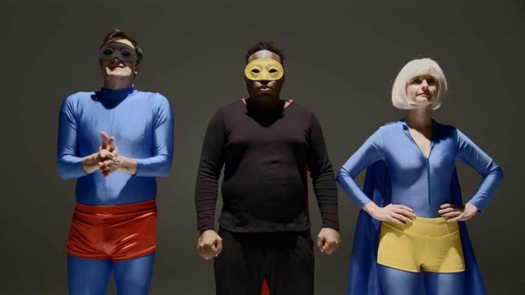 Three people dressed in superhero costumes with dim lighting
