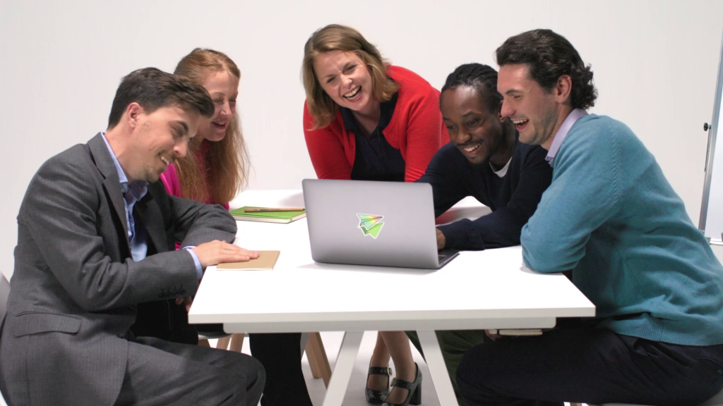 People gathering around a laptop laughing.