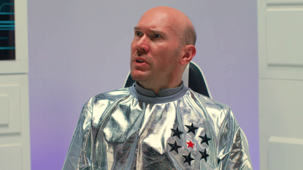 Alex McQueen dressed in space suit looking concerned.
