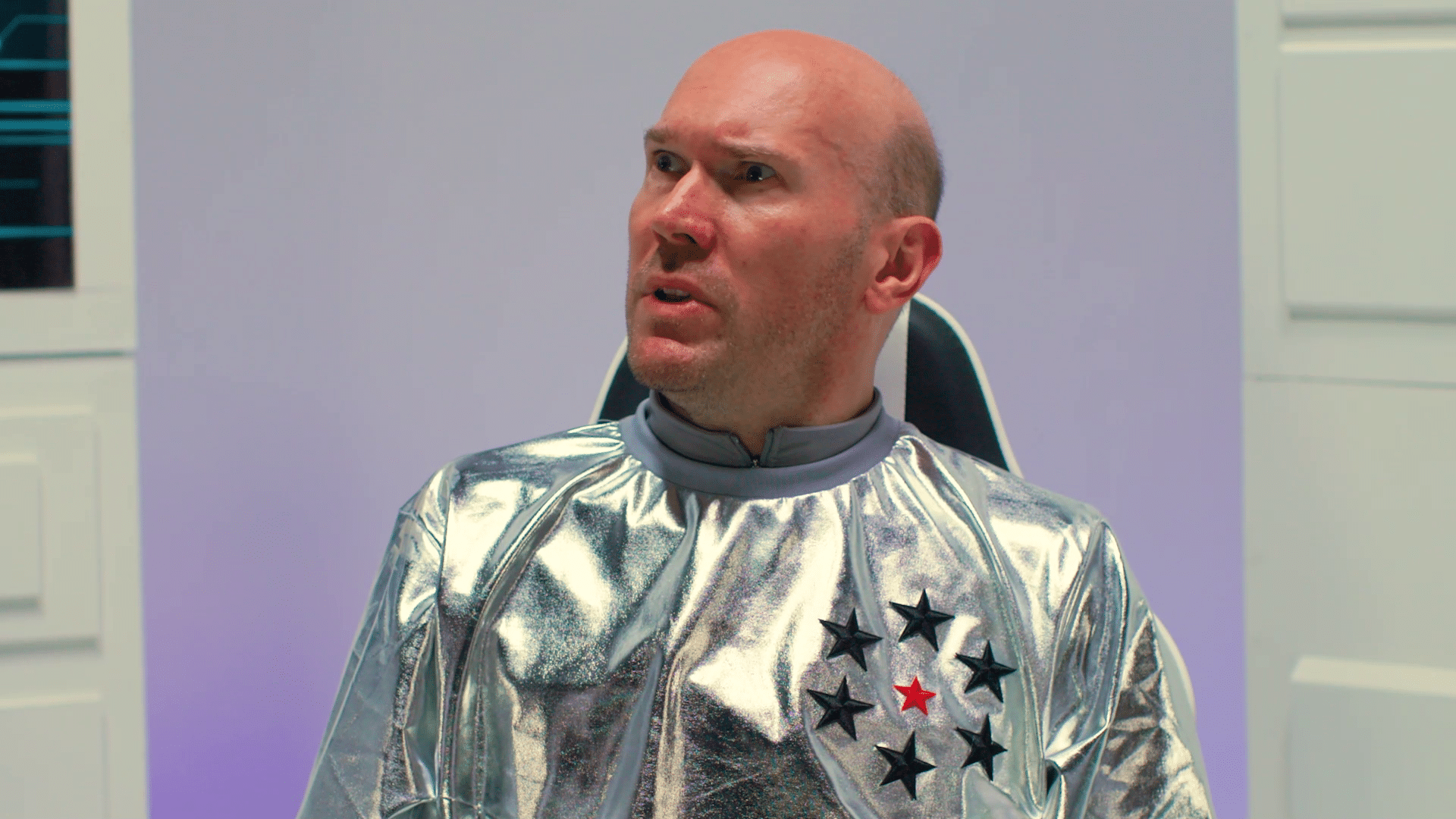 Alex McQueen dressed in space suit looking concerned.