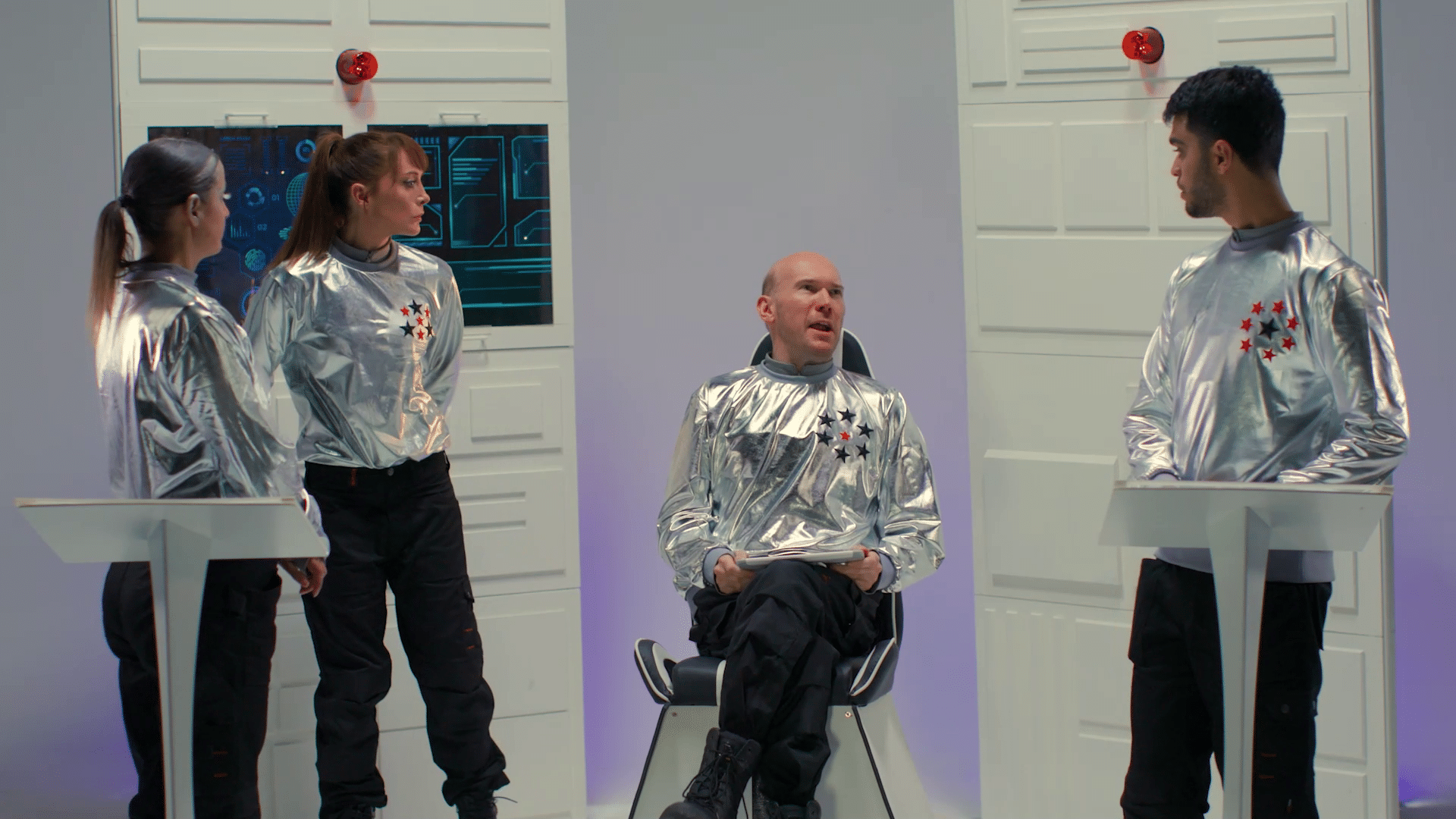 Four people wearing space suits in a spaceship