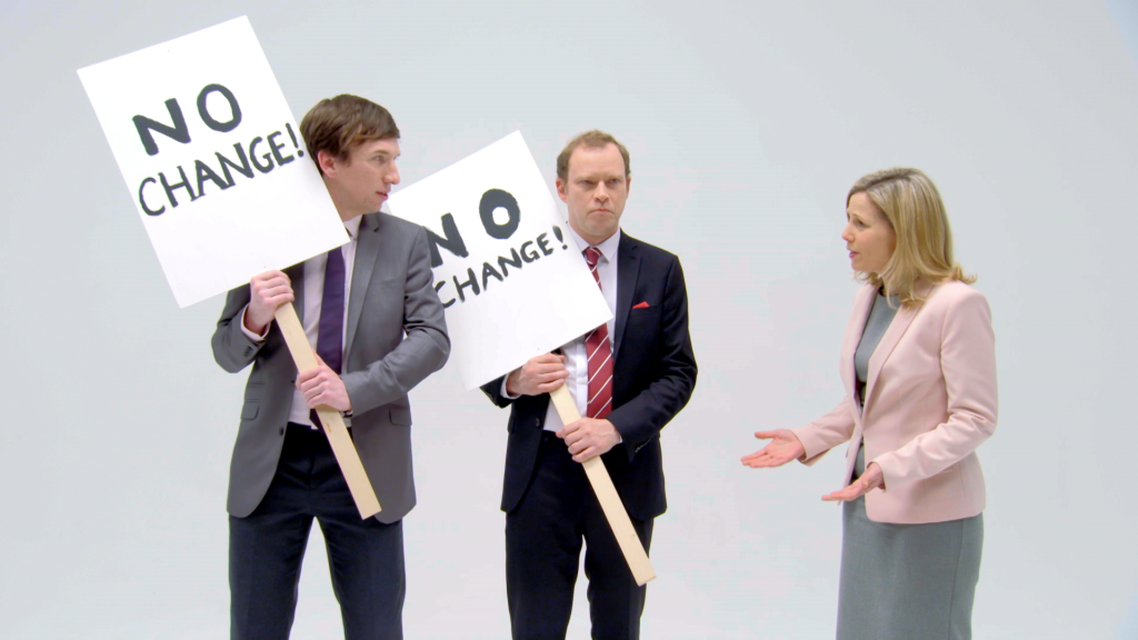 Two men stood with signs protesting change next to Sally Phillips